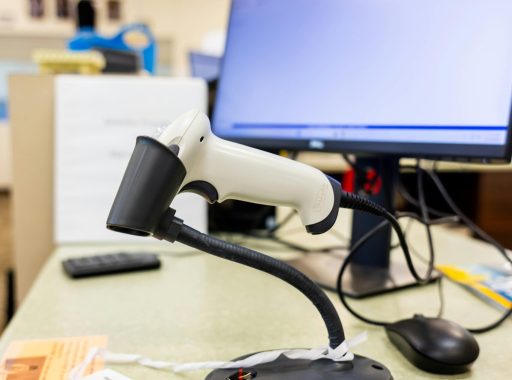 Close-up of a barcode scanner on an office desk with a computer screen in a modern workspace.